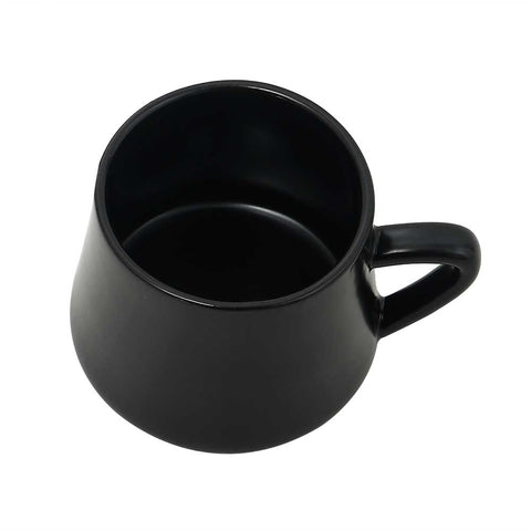 Black porcelain coffee mug from the 12-piece coffee and tea set with metal stand, placed on a floor chair.
